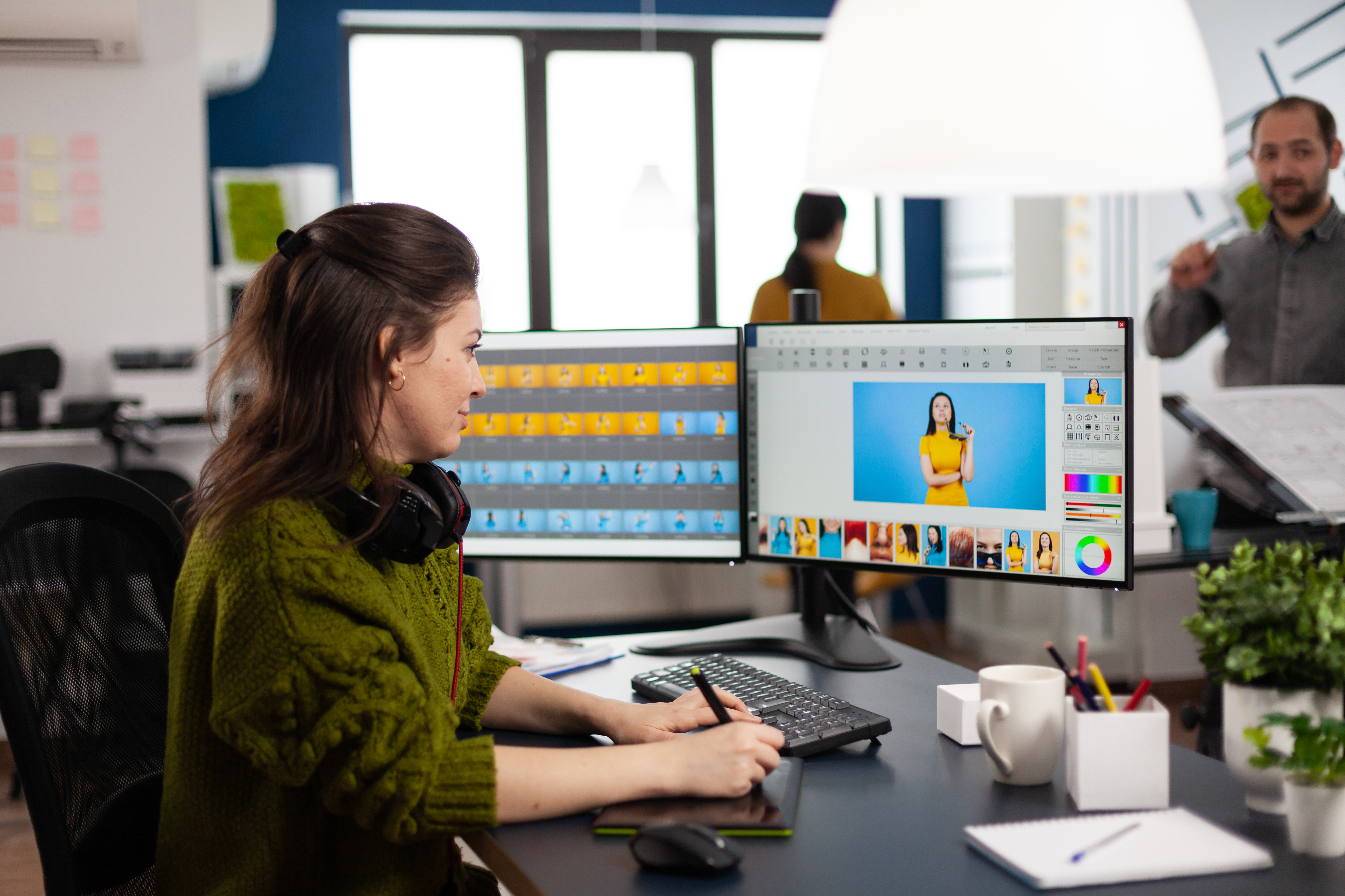Retoucher woman editor working on computer with two monitors and stylus pencil in photo editing software sitting in creative agency office. Graphic designer retouching client photos using image app